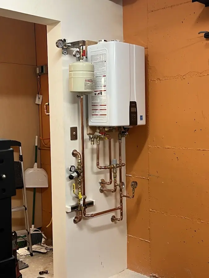Plumbing technician inspecting water heater connections in Patchogue